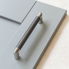 a close up of a metal handle on a gray door with a white wall in the background