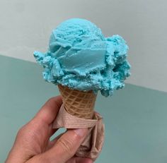 a hand holding an ice cream cone with blue icing