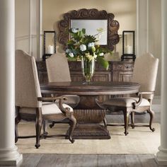 a dining room table with chairs and a mirror on the wall above it is surrounded by columns