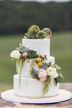 a white wedding cake with succulents and greenery