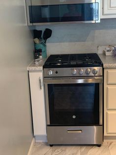 a stainless steel stove and oven in a kitchen with white cabinets, marble counter tops and flooring