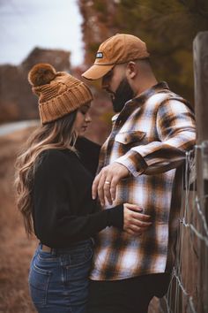 a man and woman leaning against a fence with their hands on each other's shoulders