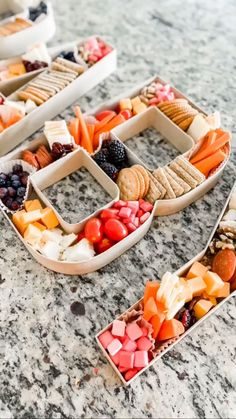 three trays filled with different types of food on top of a marble countertop