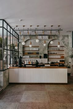 an empty restaurant with lots of counter space and hanging lights above the bar, along with potted plants