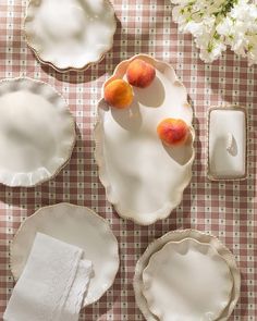 three peaches and two plates on a checkered table cloth