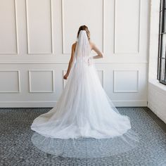 a woman in a wedding dress looking out the window