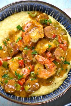 a bowl filled with shrimp and grits covered in gravy on top of a table