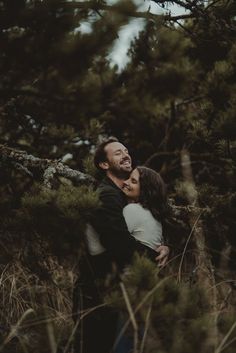 a man and woman hugging in the woods