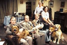 a group of people sitting in a living room with two dogs