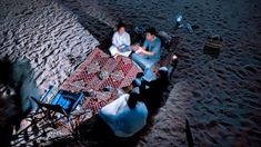 two people sitting at a table on the beach