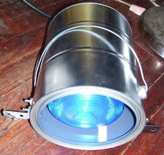 a blue light that is on top of a metal object in the middle of a wooden floor