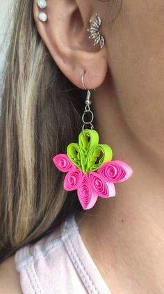 a close up of a person wearing earrings with flowers on the front and back of them