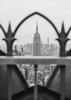 the empire state building is seen through an iron fence