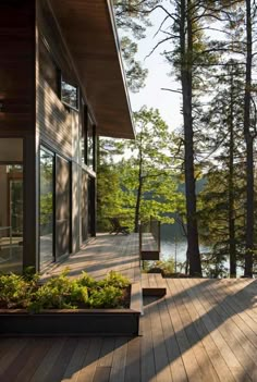 a wooden deck next to a lake surrounded by trees