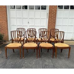 set of six chairs with caned back and wicker seats in front of a garage door