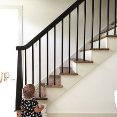 a toddler sitting on the floor in front of a stair case next to a set of stairs