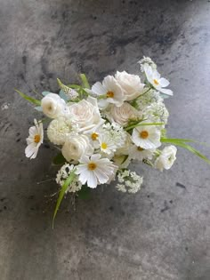 a bouquet of white flowers sitting on top of a cement floor next to a wall