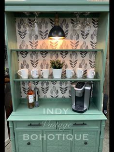 a green cabinet with cups on it and a coffee maker