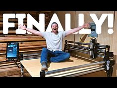 a man sitting on top of a wooden table next to a machine with the words finally