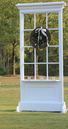 a white gazebo with a wreath on it in the middle of a grassy area