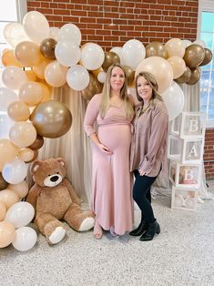 two pregnant women standing in front of balloons