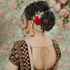 a woman with a flower in her hair wearing a red and white sari,