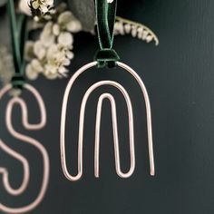 the letter s is made out of metal wire and hangs from a green cord on a black background