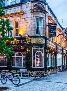 the front of a hotel with tables and chairs on the sidewalk in front of it