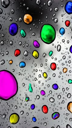 colorful drops of water on the surface of a glass window with multicolored bubbles