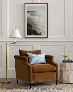 a living room with a chair, lamp and painting on the wall