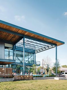 people are sitting at tables under an awning on the side of a large building