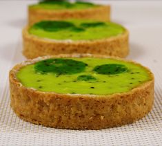 three pieces of bread with green toppings on them sitting on a white tablecloth