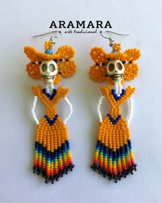 a pair of beaded earrings with a skeleton wearing a hat and tie on it