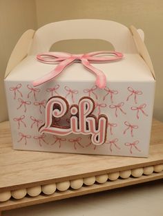 a white box with pink ribbon and the word p r y on it sitting on a wooden table