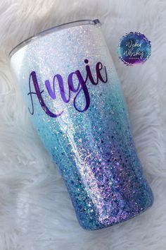 a blue and purple glitter tumbler with the name agnes on it sitting on a white furnishing