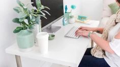 a woman sitting at a desk with a computer on her lap and plants in front of her