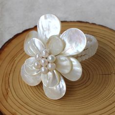 a white flower on top of a piece of wood with pearls in the center,