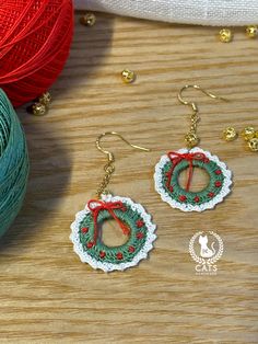 two crocheted earrings are sitting on a table next to balls of thread and yarn