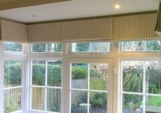 a living room filled with lots of windows next to a wooden table and couches