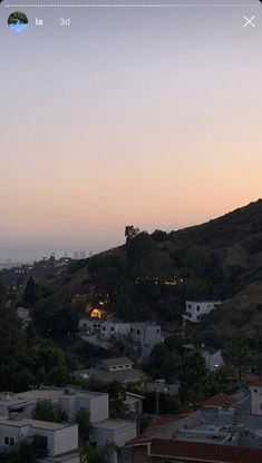 the sun is setting over some buildings and hills