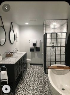 a bathroom with black and white tile flooring next to a bathtub, sink and shower