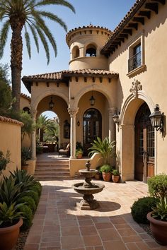 an outdoor courtyard with a fountain and potted plants in front of the entrance to a house