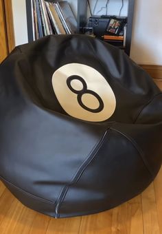 a black bean bag chair sitting on top of a hard wood floor next to a book shelf