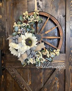 a wreath with white flowers and greenery on a wooden door