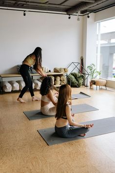 three women doing yoga in a large room