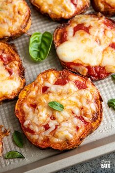 mini pizzas with cheese and basil on a baking sheet