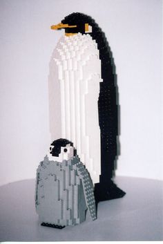 a penguin made out of legos sitting on top of a white table next to another penguin