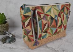 a multicolored purse sitting on top of a counter next to a potted plant