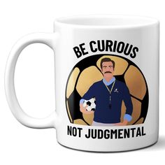 a white coffee mug with an image of a man holding a soccer ball and the words be curious not juggment