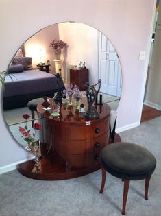 a mirror sitting on top of a dresser next to a footstool in a room